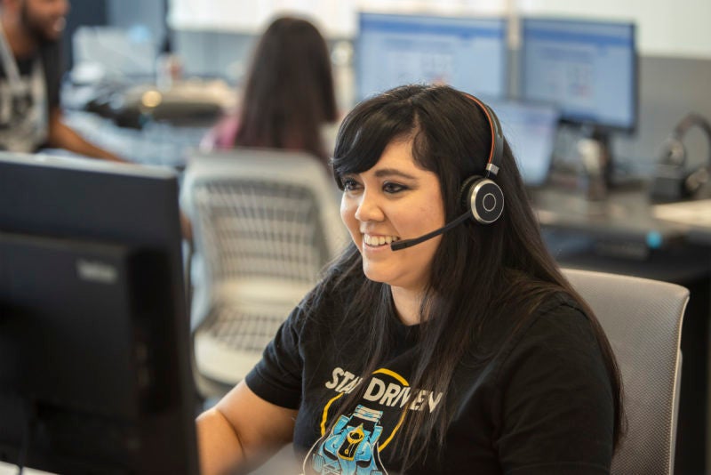 female employee smiling at desk talking to customer on headset